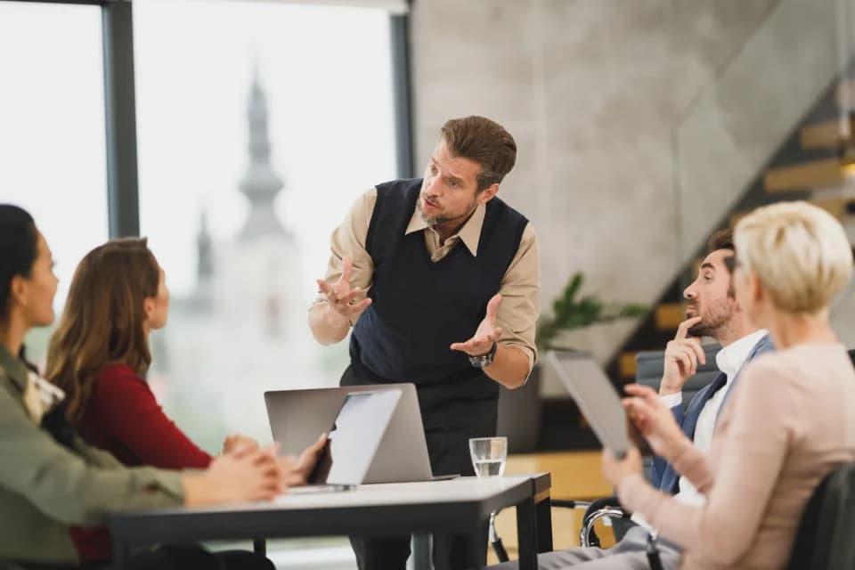 A team member presenting to attentive colleagues in a bright meeting room.
