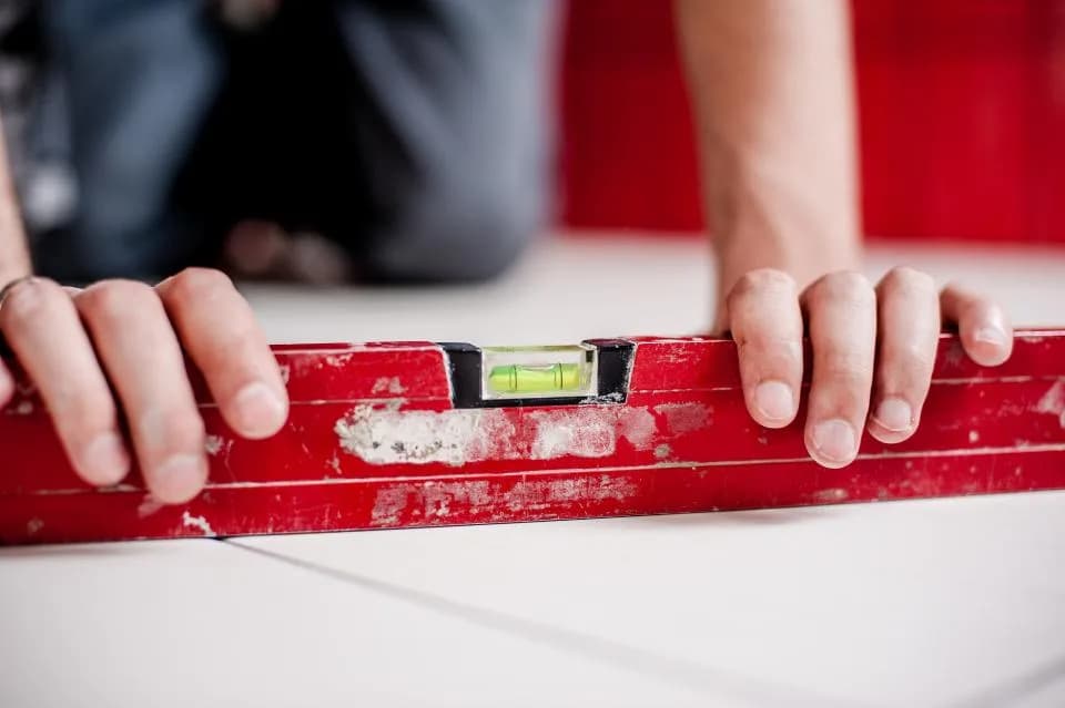 Hands placing a red spirit level on a surface to check it is level.