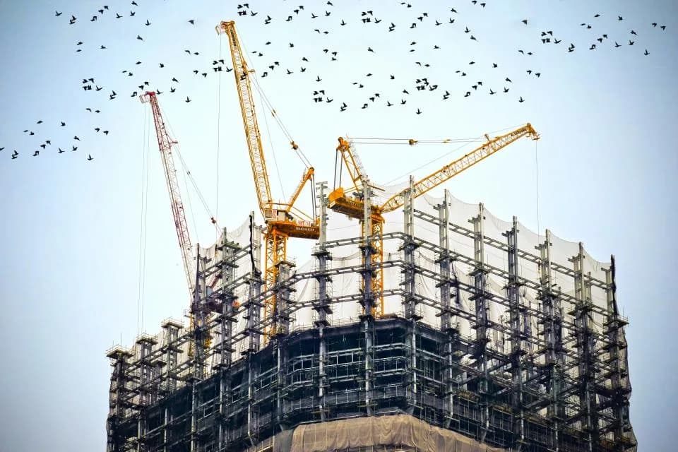 Tower cranes above a high-rise building under construction.